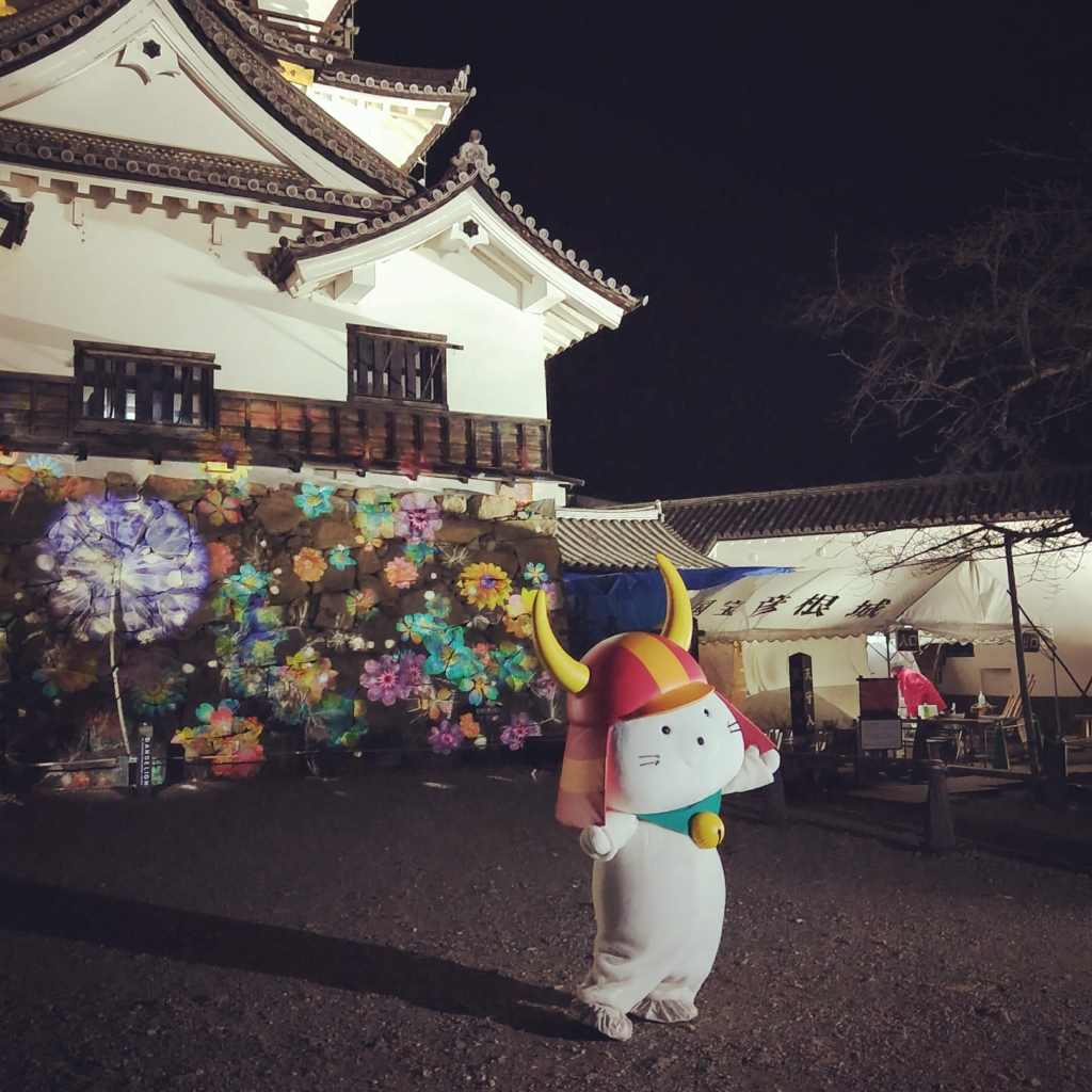 彦根城夜間特別公開の花アートNAKED GARDEN ONE KYOTOの前でポーズを決めるひこにゃん